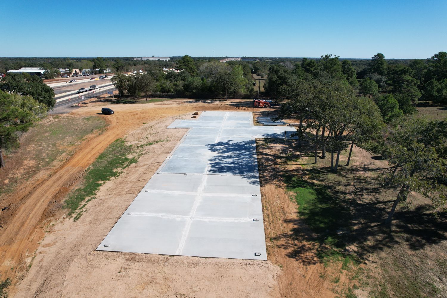 side aerial view of concrete slab foundation for 50x235 metal building near Columbus Texas